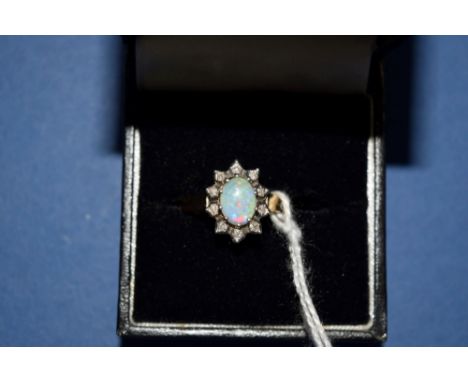 A 9ct gold ring set oval opal surrounded by ten small diamonds.   Condition Report:  Size: M - N.    Stone: 5mm x 7mm  Condit