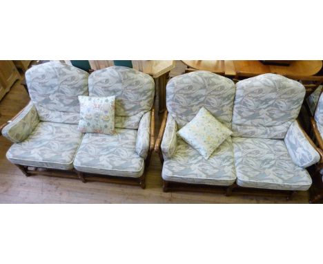 A good quality Ercol medium oak three piece suite comprising two two seater sofas, armchair and pouffee
