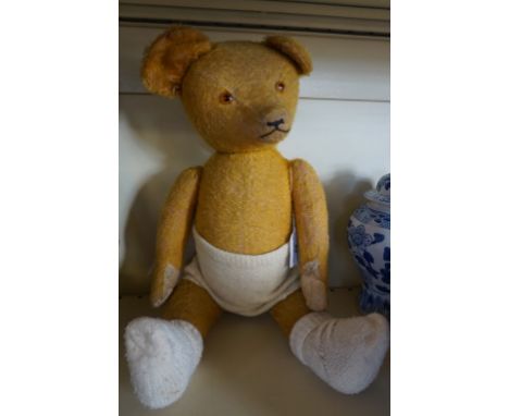 A 1920s American gold plush teddy bear, with glass button eyes, pointed snout and articulated limbs, height 52cm.