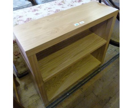 A modern light oak finished bookcase having single adjustable shelf.