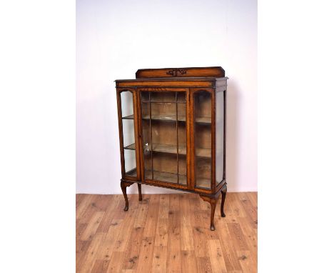 An early 20th Century oak glazed bookcase, the raised stub gallery back with foliate embellishments, over a single door cabin