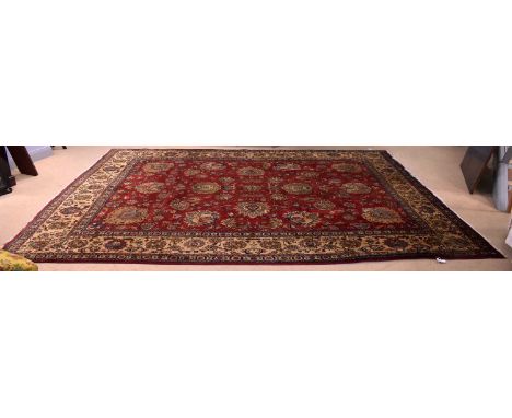 A vintage 20th Century Persian Islamic style carpet, the red ground, encompassed by a cream border, with polychrome foliate d