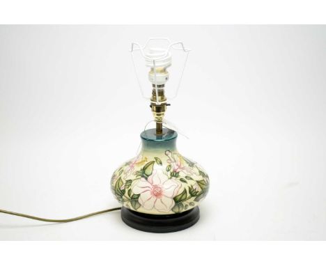 A Moorcroft table lamp, tubeline decorated with pale pink flowers on a cream ground, raised on an ebonised base, approximatel