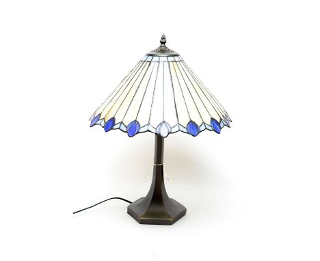 A Tiffany style table lamp, with cream and blue leaded glass style shade, raised on a hexagonal trumpet base, wired for elect