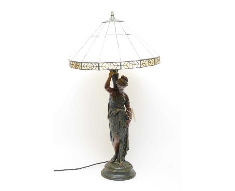 A Victorian style bronzed figural table lamp, formed as a lady in a flowing gown, holding an urn vase, with leaded Tiffany gl