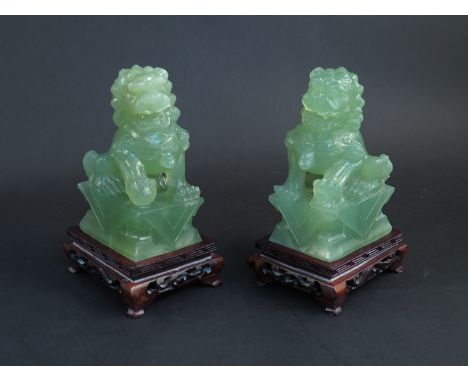 A pair of early 20th Century carved jade lions on stands, 15cm tall