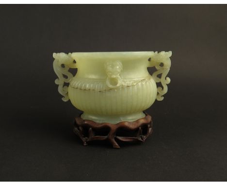 A Burmese Jade twin handled urn with melon fluted base fracture line present, on wooden stand approx 6.5cm tall x 12cm long