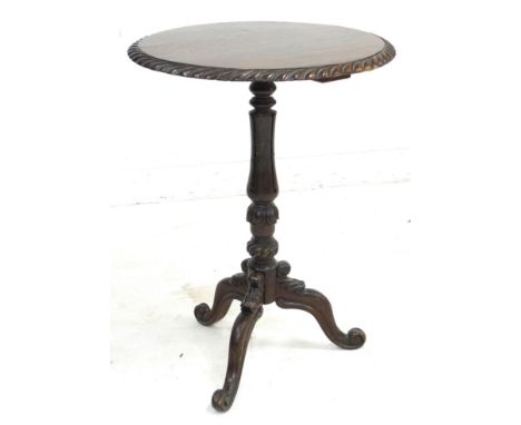 A late Victorian oak wine table, the circular surface with carved gadrooned edge, raised on a lappet carved column and carved