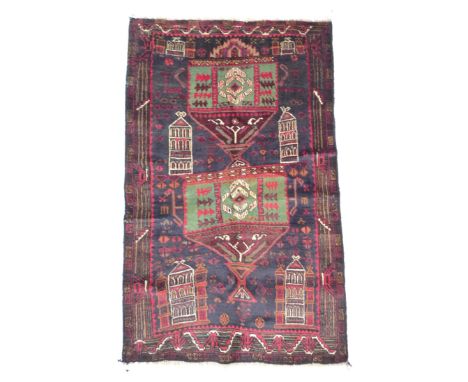 A dark blue ground Old Beluchi rug, decorated with architectural designs, 134 by 82cm. 