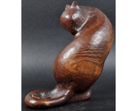 A contemporary 20th Century stained carved walnut figure / sculpture of a sitting cat grooming itself. Makers label to the ba