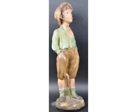 A vintage 20th Century Art Deco Chalk Ware hand painted figure of a young boy with his hands in his pockets and appears to be