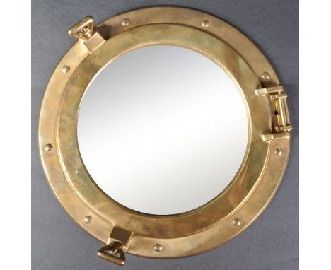 A 20th Century nautical / maritime ships brass porthole mirror of decorative form with hinge and locks housing the circular m