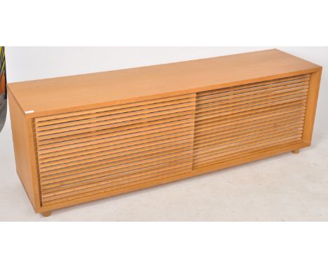 A contemporary designer blonde oak low sideboard credenza / media / H-Fi stand having two louvre sliding doors concealing a s