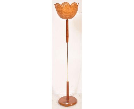 A retro vintage mid 20th Century teak and brass column uplighter / standard lamp light having a circular base with wicker sha