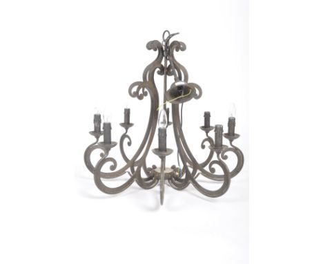 A late 20th Century Gothic influenced chandelier of pressed iron construction having a series of scrolled arms with ceiling b