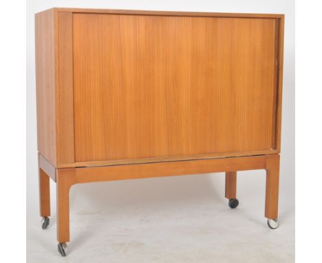 A retro mid 20th Century 1960s Danish teak tv media cabinet having a single sliding tambour door opening to reveal a hollow i