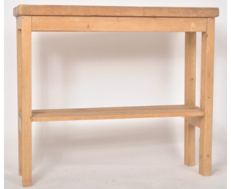 A 19th Century pine topped kitchen island / console table of long slender form having a planked top raised on a later chunky 