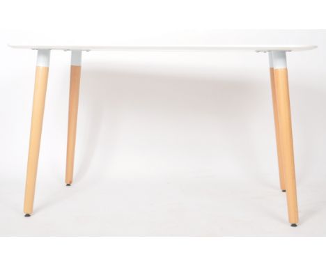 A contemporary Scandinavian influenced dining table of round rectangular form having a white laminated top raised on four ash