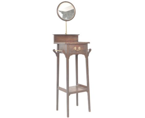 An early 20th Century oak vanity wash / dress stand having a circular oak framed mirror supported by single brass stem. Below