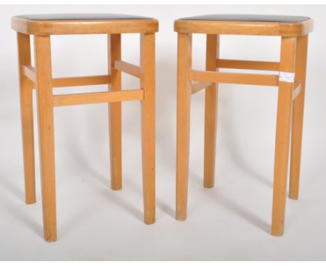 A matching pair of retro mid 20th Century bentwood stools with each having black rexine padded tops raised on tapering suppor