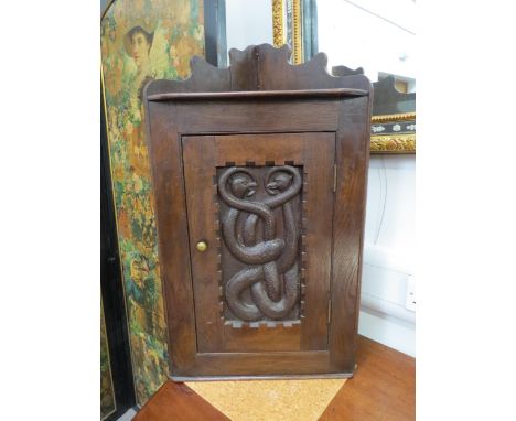 A late Victorian oak corner cupboard with carved mythical beast panel door, shelf to interior, 78cm x 44cm x 32cm