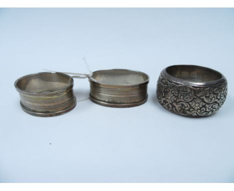 A heavily embossed napkin ring, engraved to interior 'J.E.B. FEB 22nd 1907' and a pair of silver napkin rings, Birmingham 193