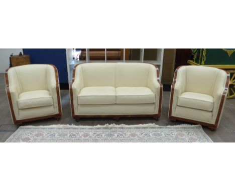 An Art Deco walnut and cream leather suite consisting of two seater settee and a matching pair of armchairs, each raised on c