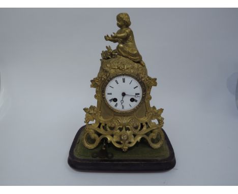 A late 19th century French ormolu mantel clock surmounted by child and rabbit with grape and vine styling, while enamel dial,