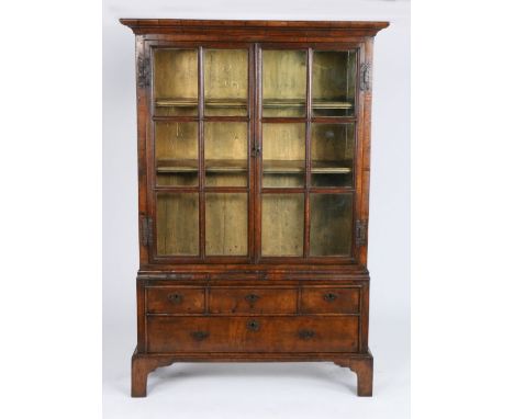 A small George I walnut and oak bookcase cabinet, circa 1720 and laterIn two parts, with cyma-recta cornice, and a pair of ei