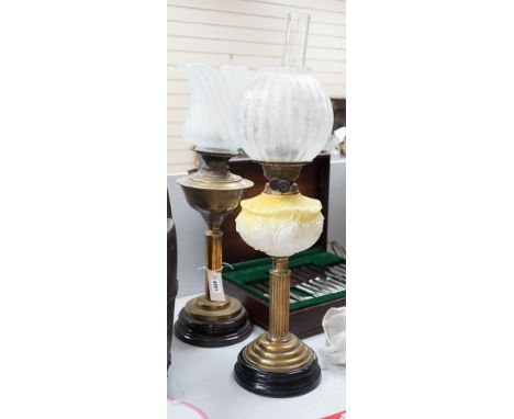 A brass and glass oil lamp and another brass oil lamp, both with shades, tallest 67cms high,