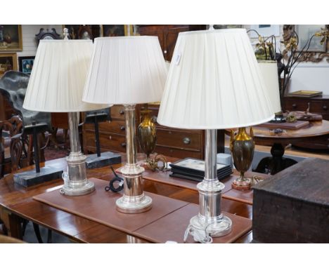 A pair of steel column table lamps, with matching cream silk shades and another similar lamp and shade, pair 96cms high,