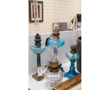 Three blue glass oil lamps and a clear glass oil lamp, tallest 62cms high,
