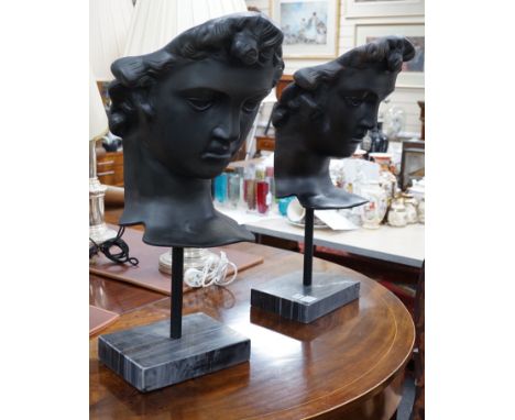 A pair of bronze masks of youths, raised on marble plinths,78cms high,