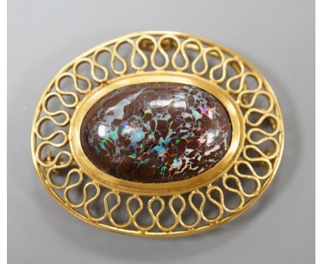 A continental 750 yellow metal and large oval boulder?&nbsp; opal set pendant brooch, with a filigree scroll border, 47mm, gr