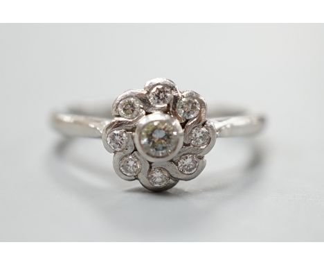 A modern platinum and nine stone diamond set flower head cluster ring, size O, gross weight 5.4 grams.