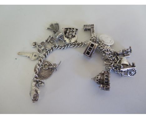 A silver charm bracelet with various silver and white metal charms, including Big Ben, Brighton Pavillion etc - approx 61 gra