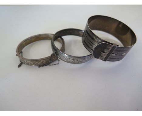 Three silver bangles, two with engraved floral decoration, the other of belt design, approx 70 grams 