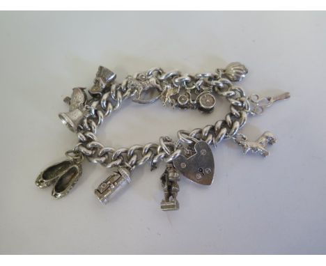A heavy silver charm bracelet with various silver and white metal charms - approx 81 grams 