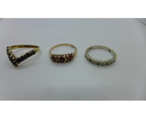 Three 9ct gold rings, wishbone set with sapphires, size O, seven stone garnet, size R, and an emerald and white stone half et