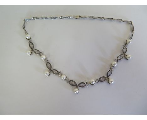 A silver necklace with textured detail set with pearls 