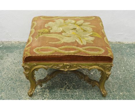 A French style carved giltwood stool, X-form stretcher with central finial boss, upholstered in woolwork with lilies and rope