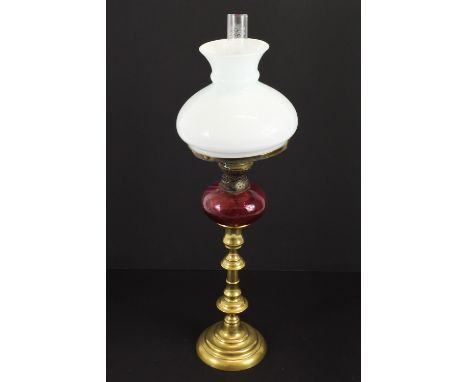 A table oil lamp of small size, cranberry glass oil well on brass candlestick base