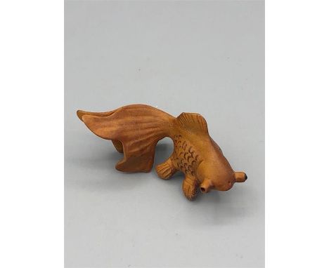 A wooden Japanese Netsuke in the form of a fish signed to the base