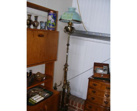 An adjustable brass standard lamp with light green glass shade