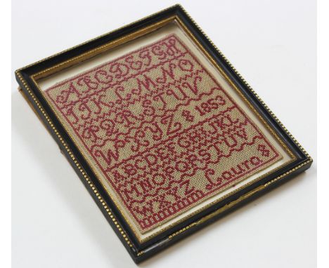 Miniature alphabetical sampler in wool on cloth, named Laura 1853 in a period ebony and gilt frame