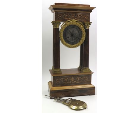 19th century mantle clock decorated in the classical manner with columns and extensive gilding around a steel dial with roman