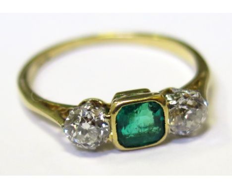 Ring stamped 18ct with central Emerald and two 0.20ct Diamonds size K weight 1.9grams