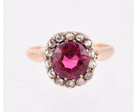 
	
		AN EARLY 20TH CENTURY SYNTHETIC RUBY AND DIAMOND RING 
		The oval cut synthetic ruby within a surround of rose cut diamo