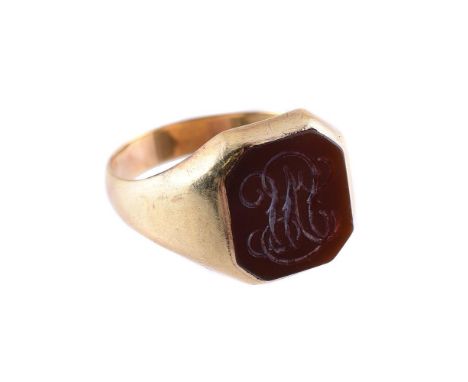 
	
		A CORNELIAN AND GOLD COLOURED SIGNET RING 
		The polished octagonal panel engraved with a scrolled monogram, to tapering