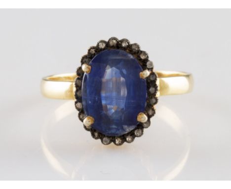 A yellow metal kyanite and diamond cluster ring, set centrally with an oval cut kyanite, measuring approx. 11x9mm, surrounded